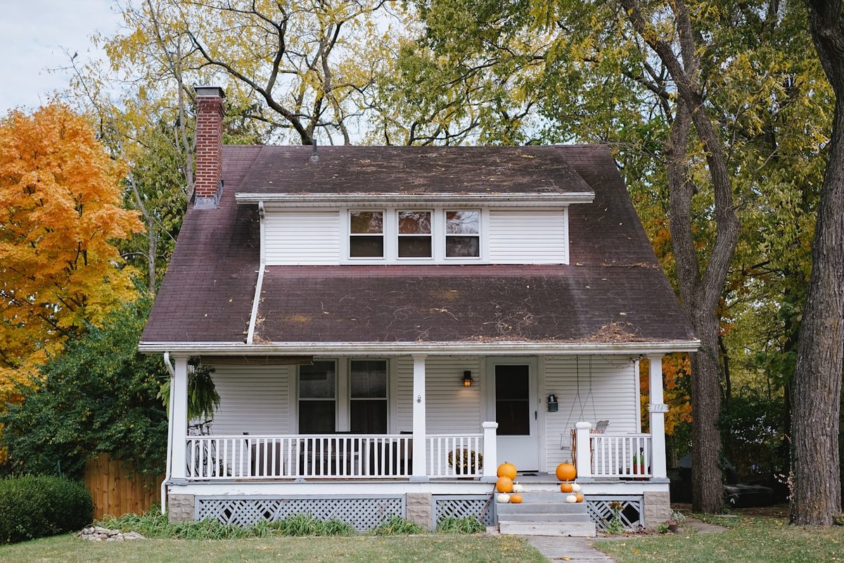 White traditional two-story home with a covered front porch on a tree-lined street in Springboro, Ohio